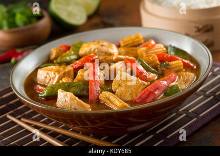 Deliziosa casa tailandese curry rosso con pollo, pepe rosso, neve piselli, baby mais, latte di cocco e coriandolo. Foto Stock