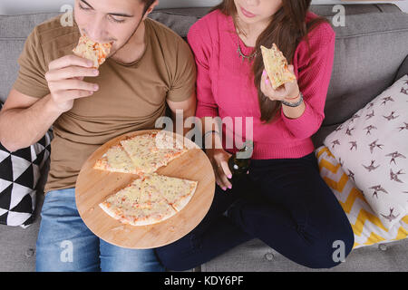 Bella coppia Giovane a bere birra e mangiare la pizza. in ambienti chiusi. Foto Stock