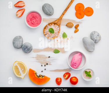 In casa di cura di pelle e scrub corpo rosso con ingredienti naturali fragola , Pomodoro ,Sale Himalayano,papaia, la carota e la pietra sul bianco backgrou in legno Foto Stock