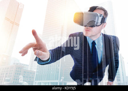 Imprenditore in cuffia vr pronto a toccare qualcosa con il dito Foto Stock