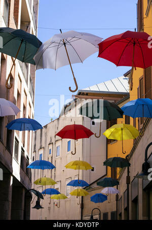 Floating ombrelloni colorati in italiano street a Ravenna Italia. Cielo blu, strada stretta con antenna ombrelloni. Insolito arty. colorata e felice. Foto Stock