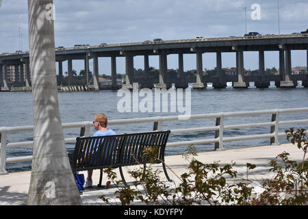 Uomo seduto sul banco a riverwalk affacciato sul fiume Manatee in Bradenton Florida Foto Stock