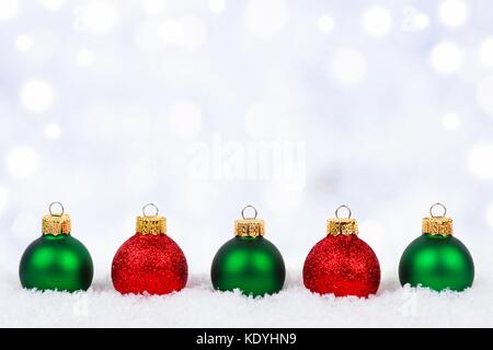 Rosso e verde di Natale ornamenti nella neve con il luccichio sfondo color argento Foto Stock