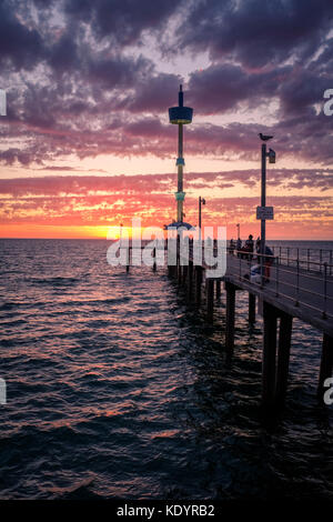 Le persone godono di un magnifico tramonto al mare di Adelaide del molo di Brighton su una mite serata d'estate. Foto Stock