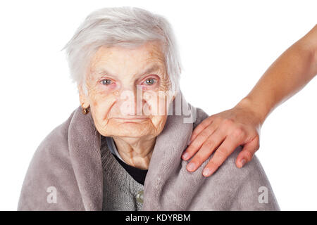 Senior donna malata sulla isolato coperto da una calda coperta caregiver sta aiutando le mani Foto Stock