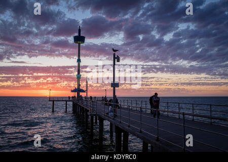 Le persone godono di un magnifico tramonto al mare di Adelaide del molo di Brighton su una mite serata d'estate. Foto Stock