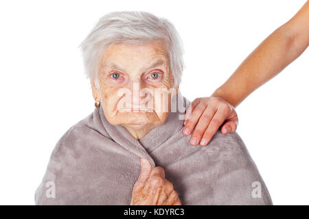 Senior donna malata sulla isolato coperto da una calda coperta caregiver sta aiutando le mani Foto Stock