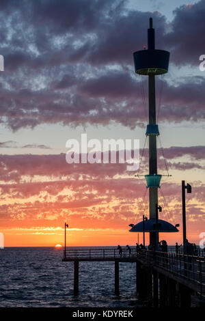Le persone godono di un magnifico tramonto al mare di Adelaide del molo di Brighton su una mite serata d'estate. Foto Stock