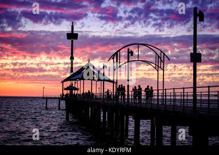 Le persone godono di un magnifico tramonto al mare di Adelaide del molo di Brighton su una mite serata d'estate. Foto Stock