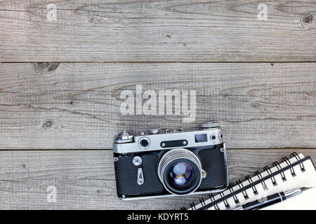 Vecchi ricordi concetto. retrò fotocamera, notebook e penna su un tavolo di legno. Foto Stock