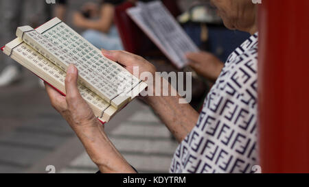 23 settembre, 2017 - Taipei, Taiwan: mani femminili che trasportano un buddista pregare libro scritto in cinese Foto Stock