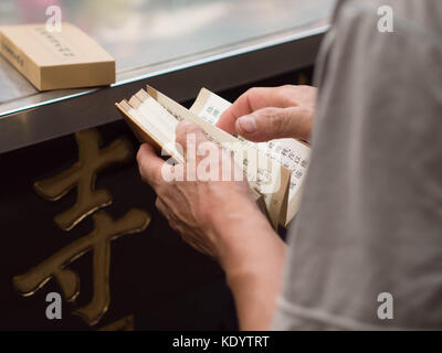 23 settembre, 2017 - Taipei, Taiwan: mani femminili che trasportano un buddista pregare libro scritto in cinese Foto Stock