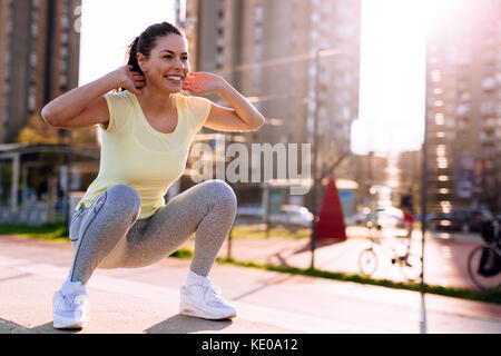 Giovane donna facendo squat in area urbana Foto Stock