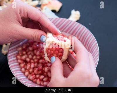 Donna peeling i semi di melograno vicino la vista superiore Foto Stock