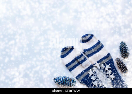 Inverno bianco Natale con sfondo bianco e a strisce blu muffole, tre abete rosso dipinto di blu coni, un grande simbolo del fiocco di neve e copia di spazio. Foto Stock