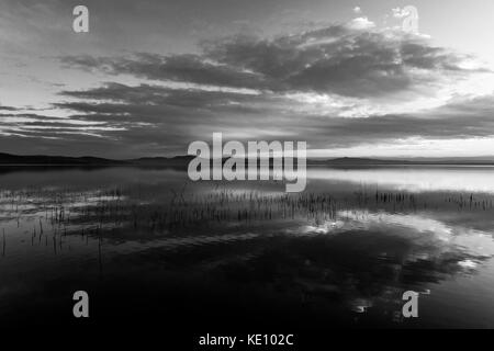 Perfetta e simmetrica nuvole riflessioni su un lago al tramonto Foto Stock