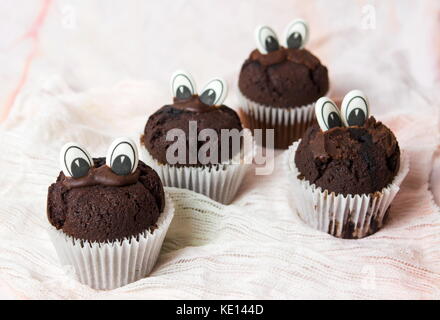 Muffin al cioccolato con occhi commestibili in titolari della carta Foto Stock