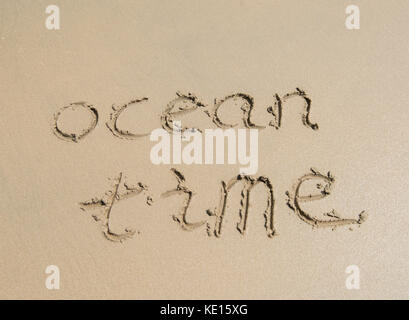 Tempo oceano parole scritte nella sabbia sulla spiaggia Foto Stock