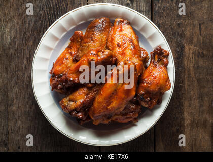 Una piastra del barbecue affumicati ali di pollo con canditi bbq sauce rustico superficie in legno Foto Stock