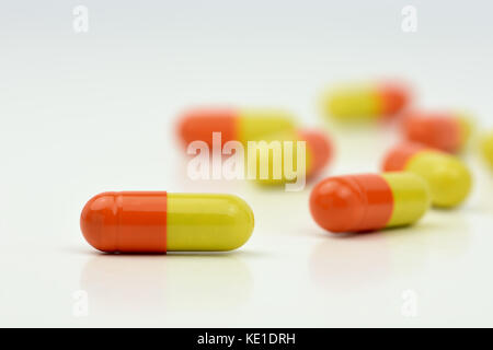 Close-up foto di giallo arancione pillole isolato su sfondo bianco con sfondo sfocato Foto Stock
