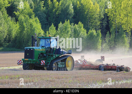 Salo, Finlandia - 27 maggio 2016: John Deere 9520t trattore cingolato e coltivatore sul campo di stoppie a molla nel sud della Finlandia. Foto Stock