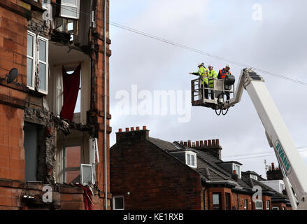 I lavoratori rilevano i danni di un blocco di appartamenti a Crosshill, nella parte sud di Glasgow, dopo che parte del fronte è stato abbassato in alto venti come Storm Ophelia spazzano attraverso la Scozia. Foto Stock