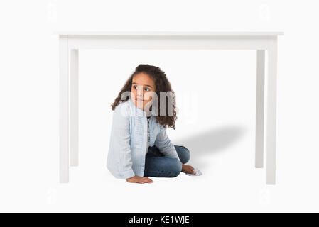 Adorabili americano africano ragazza seduta sotto la tabella isolato su bianco Foto Stock