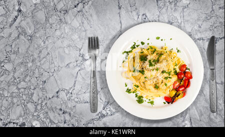 Fresche fatte a mano le tagliatelle con funghi di bosco, il prezzemolo e i pomodori ciliegia insalata di granito sul bancone della cucina. vista superiore con spazio copia adde Foto Stock