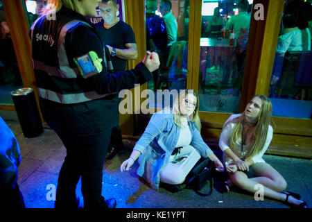 Email lady portiere pub parlando di sicurezza a tarda notte festaioli sabato sul pavimento sul lungomare in Bristol Foto Stock