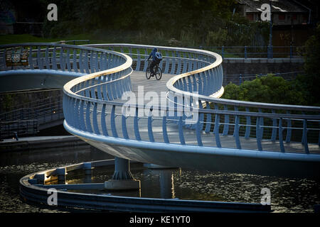 Avvolgimento pedonale passerella tra il Parco del Castello e raggiungere Finzels denominato ponte del castello nel centro città di Bristol utilizzato da un ciclista a guidare la sua bici Foto Stock