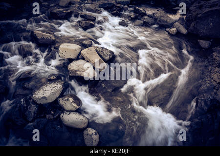 Fiume con rocce in motion blur, look vintage con grano Foto Stock