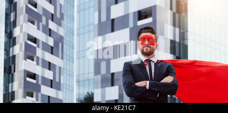 Un imprenditore in un costume da supereroe si erge contro un business b Foto Stock