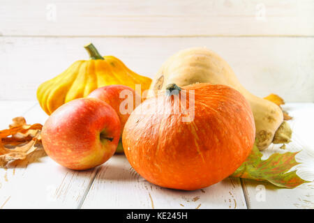 Zucca e Patty pan, mele e acero, rovere foglie gialle su una bianca tavolo in legno. raccolto autunnale. Foto Stock