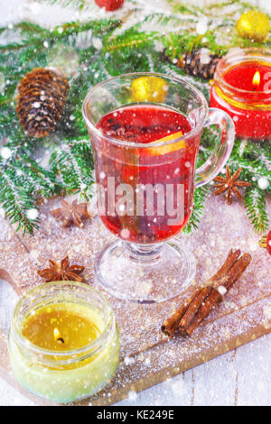 Nuovo anno vin brulé in un vetro sullo sfondo di ramoscelli, candele e ghirlande. Foto Stock