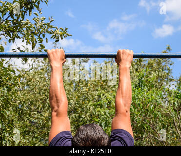 Le mani sulla barra di close-up. l'uomo tira se stesso sulla barra. La pratica di sport all'aria fresca. barra orizzontale Foto Stock