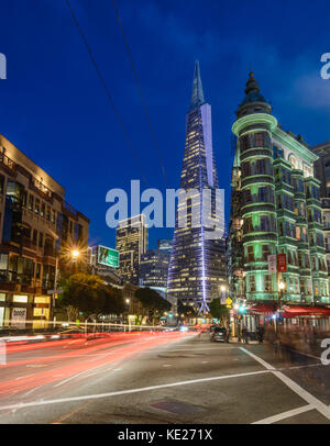 Il flusso di traffico attraverso il quartiere finanziario di San Francisco, e la spiaggia Nord lungo la Columbus Avenue di notte con Transamerica e Coppola edificio Foto Stock