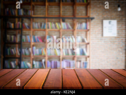 Messa a fuoco selezionata vuota brown tavolo in legno e la libreria o la libreria di sfocatura con sfondo bokeh immagine. per il fotomontaggio o display del prodotto. Foto Stock