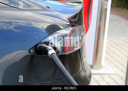 PAIMIO, Finlandia - 29 Aprile 2016: Close up nero modello Tesla S veicolo elettrico essendo caricato in Tesla Supercharger stazione di Paimio. Il verde li Foto Stock