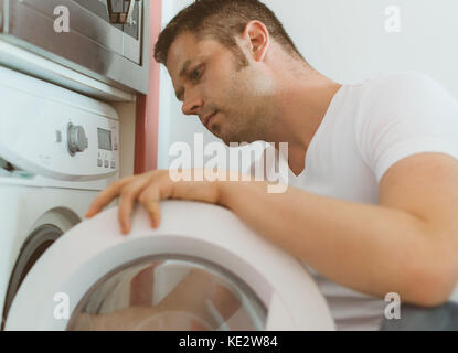 Tecnico maschile che ripara la lavatrice a casa. Foto Stock