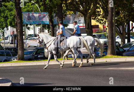 Due poliziotti portoghesi a cavallo lungo il viale principale di Albufera in Portogallo Foto Stock