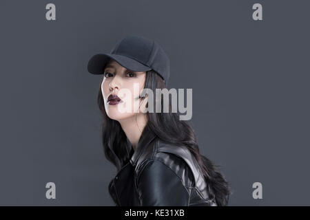 Vista laterale Ritratto di giovane donna in nero giacca di pelle e tappo nero Foto Stock