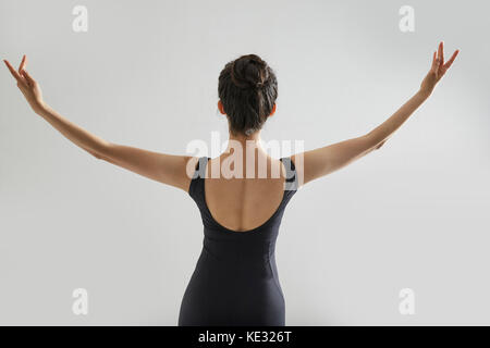 Retro del giovane ballerina in nero leotard apertura ponendo le braccia Foto Stock