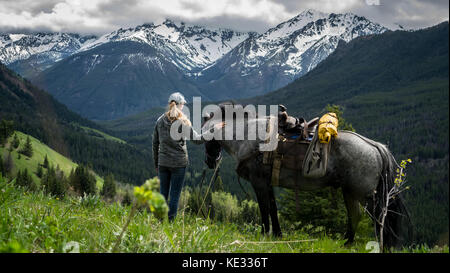 Una guida femmina e il suo azzurro Stefano castrazione che viaggiano insieme attraverso i prati alpini nel sud Chilcotin Mountain Park, BC, Canada Foto Stock