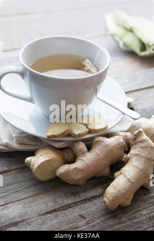 Tazza di acqua calda tè allo zenzero con fette di zenzero e radice di zenzero, orientamento verticale. Foto Stock