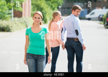 La donna grida al suo fidanzato guardando alla donna che cammina sulla strada Foto Stock