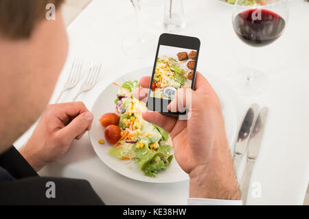 Close-up di uomo di scattare una foto di alimenti con il telefono cellulare Foto Stock