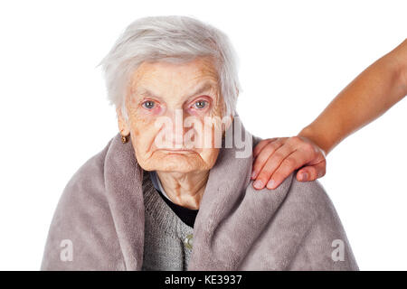 Senior donna malata sulla isolato coperto da una calda coperta caregiver sta aiutando le mani Foto Stock