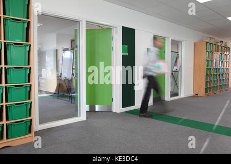 Codificati a colori corridoio in aula in una nuova Londra scuola primaria. Mostra maestro lasciando classroom - sfocato attraverso il movimento. Foto Stock