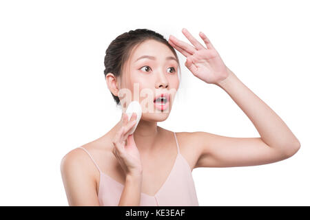 Donna con sorpresa di fronte mettendo sul make up, liquido applicato foundation sul suo viso Foto Stock