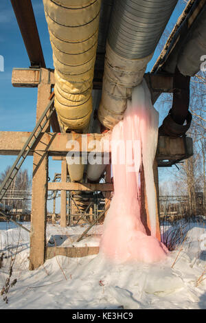 Grandi icicle rosa su di un tubo di acqua e la perdita di calore in inverno. Foto Stock